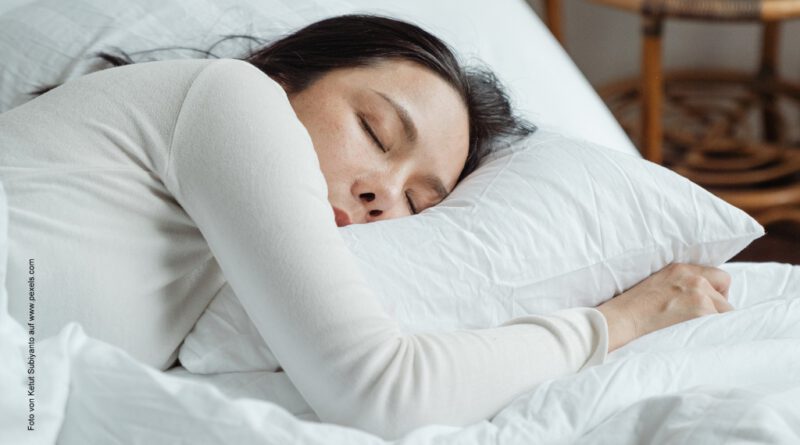 Eine Frau schläft in weißer Bettwäsche