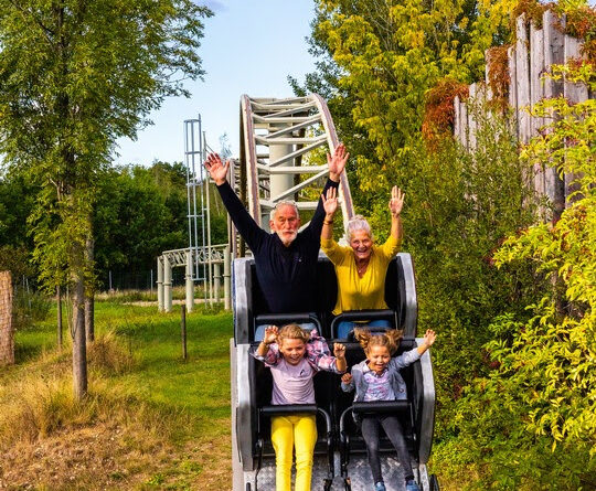 Ein Seniorenpaar mit 2 Enkelkinder in einer 8er-Bahn im Belantis Freizeitpark