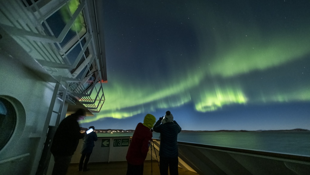 Grünes Polarlicht in Norwegen über einem Schiff