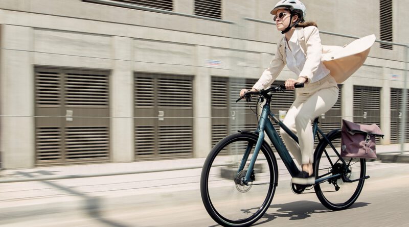 Frau im weißen Anzug und Helm auf einem E-Bike